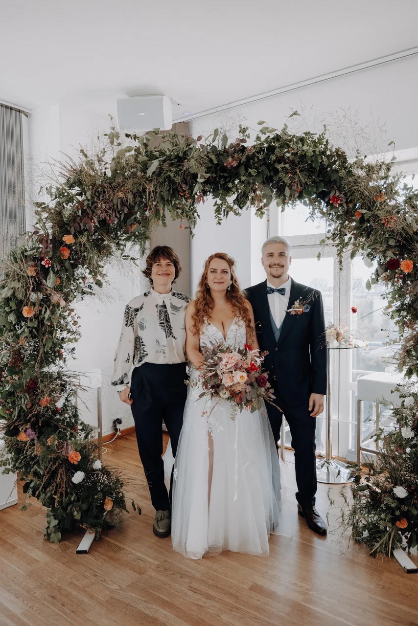 Katharina mit Brautpaar unter Blumenbogen